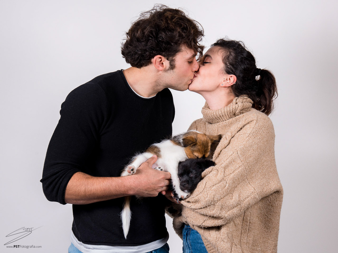Pareja se besa mientras sus perros duermen en sus brazos